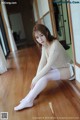 A woman sitting on the floor in white stockings.