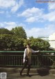 A woman standing on a bridge with her arms outstretched.