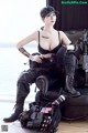 A woman sitting on top of a black chair holding a rifle.