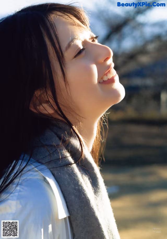 A woman with long black hair and a gray scarf.