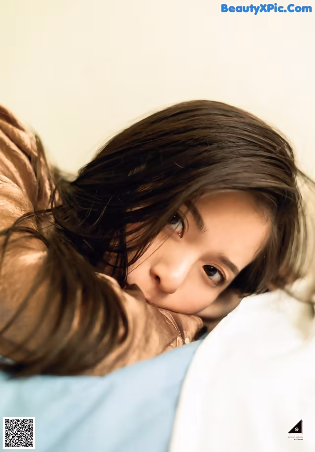 A woman laying on top of a bed next to a man.