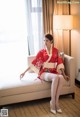 A woman in a red kimono sitting on a white couch.