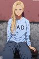 A woman sitting on a bench wearing a sweatshirt that says AD.