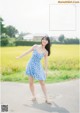 A woman in a blue dress standing in a field.