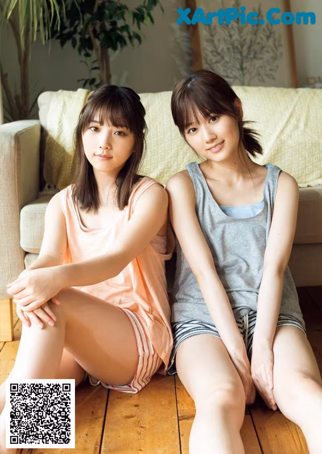Two young women sitting on the floor next to each other.