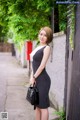 A woman in a black and white striped dress holding a handbag.