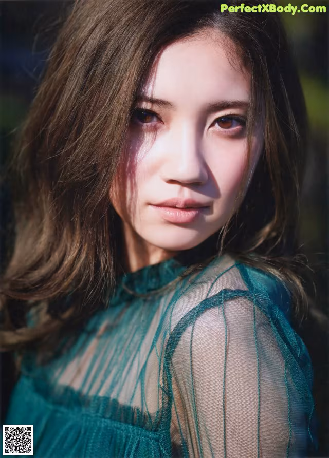 A woman with long brown hair wearing a green dress.