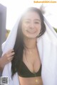 A woman in a black bikini with a white towel over her head.