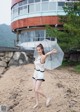 A woman standing on a beach holding an umbrella.