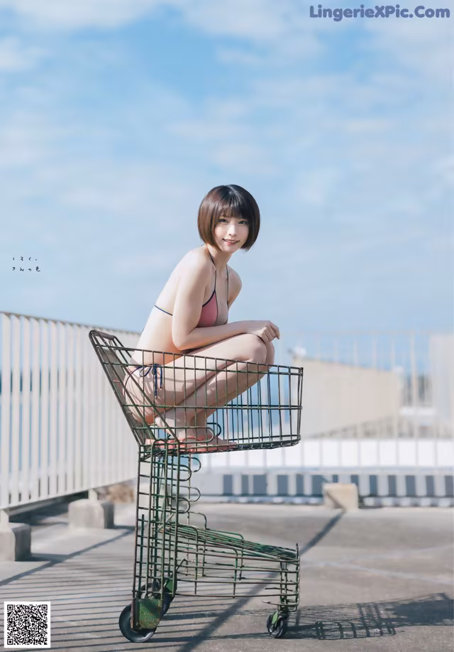 A woman in a bikini sitting in a shopping cart.