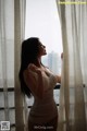 A woman in a white lingerie looking out a window.