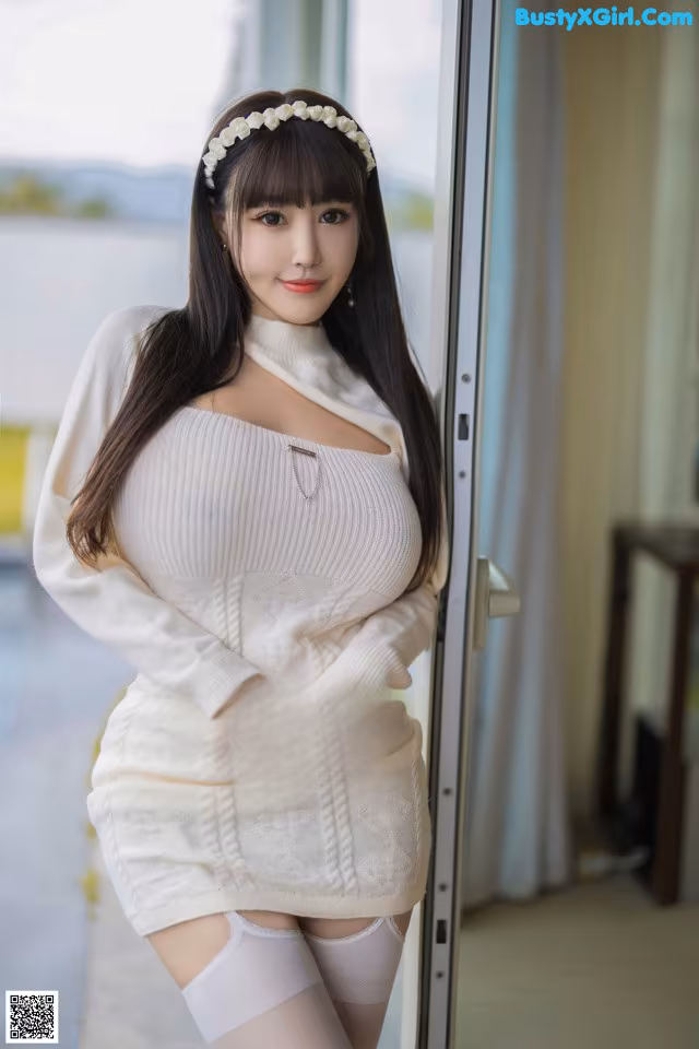 A woman in a white sweater and stockings posing for a picture.