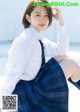 A woman in a school uniform sitting on the ground.