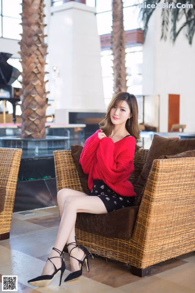 A woman sitting on a wicker chair in a lobby.