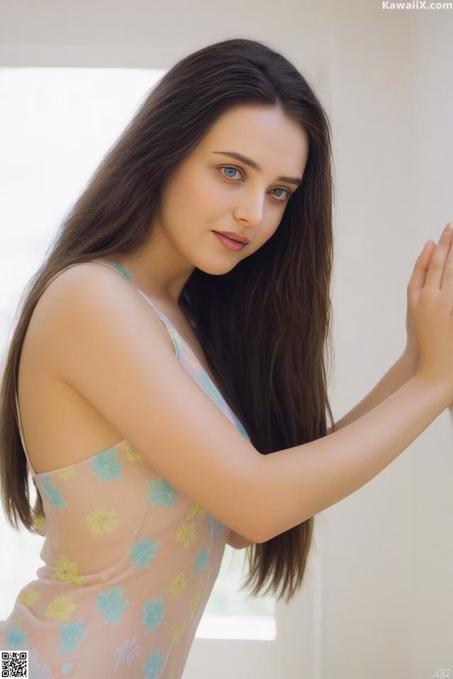A woman in a pink dress leaning against a wall.