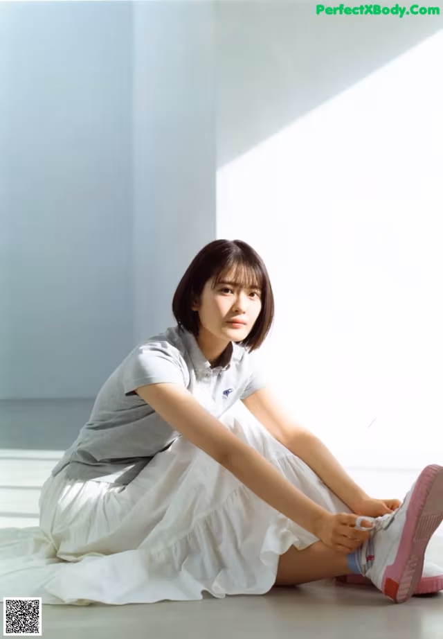 A woman sitting on the floor with her legs crossed.