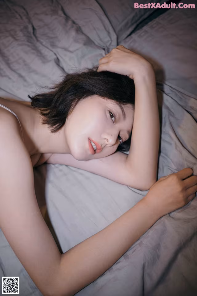 A woman laying on a bed with her head on her hands.