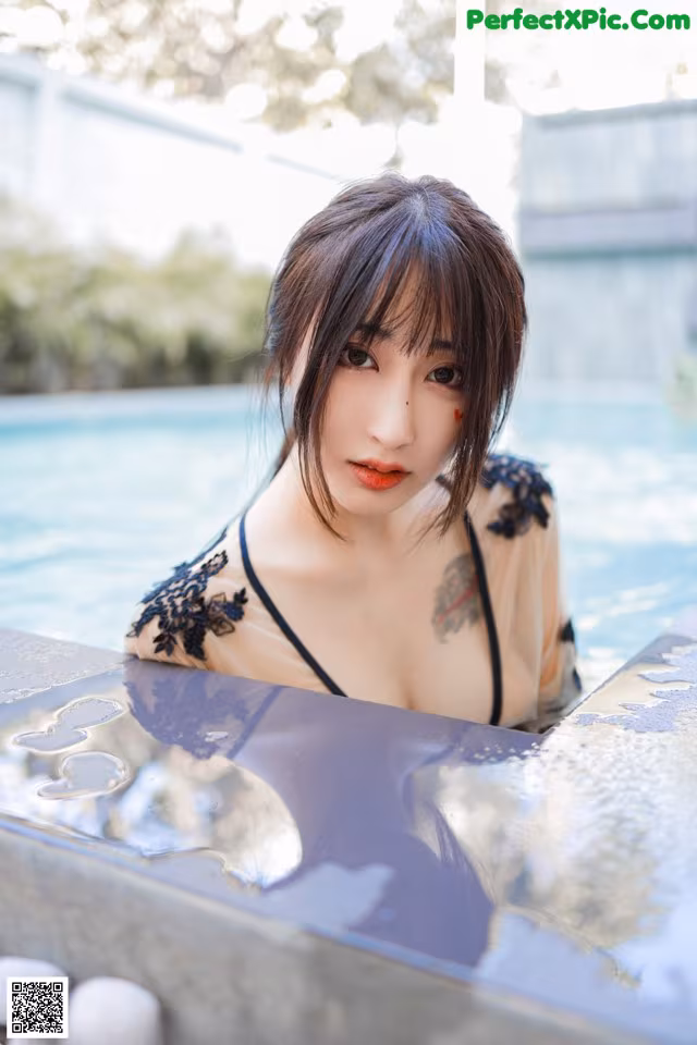 A woman in a black dress sitting in a pool.