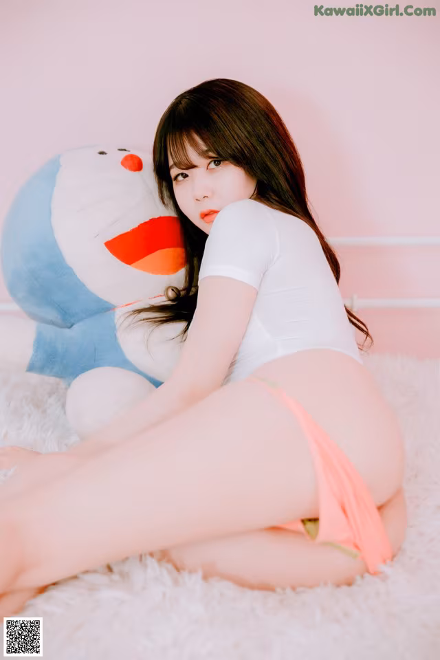 A woman sitting on a bed next to a stuffed animal.